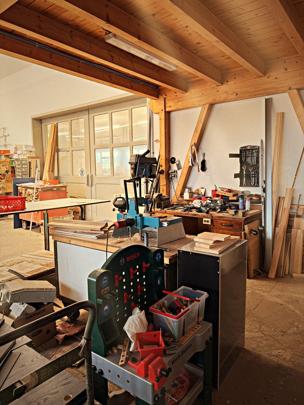 Werkbank mit Bohrmaschine und Werkzeug unter Holzbalken
